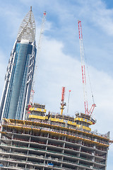 Image showing Skyscrappers construction site with cranes on top of buildings.