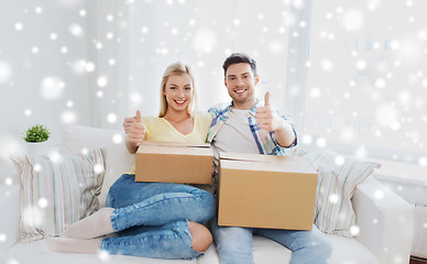 Image showing happy couple with boxes showing thumbs up at home