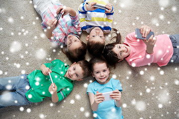 Image showing happy children with smartphones lying on floor