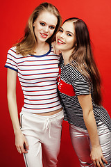 Image showing two best friends teenage girls together having fun, posing emotional on red background, besties happy smiling, lifestyle people concept