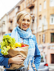 Image showing young pretty blond woman with food in bag walking on street