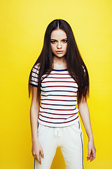 Image showing young pretty teenage woman emotional posing on yellow background, fashion lifestyle people concept