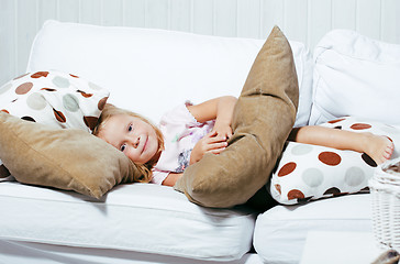 Image showing little cute blonde norwegian girl playing on sofa with pillows, lifestyle people concept