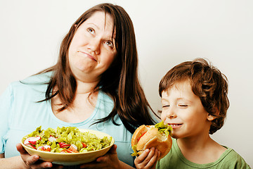 Image showing mature woman holding salad and little cute boy with hamburger te