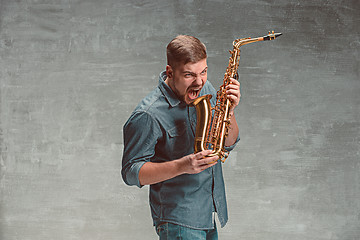 Image showing Happy saxophonist with sax over gray background