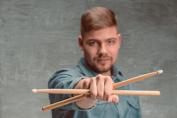 Image showing Man holding two drumsticks over gray background