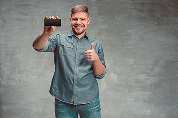 Image showing The young smiling caucasian businessman on gray background with phone