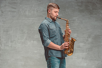 Image showing Happy saxophonist playing music on sax over gray background