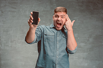 Image showing The young smiling caucasian businessman on gray background with phone