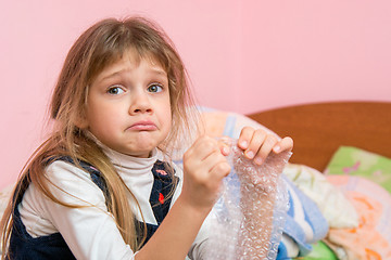 Image showing Upset girl pouting cheeks eats bubbles packaging film and looked for someone