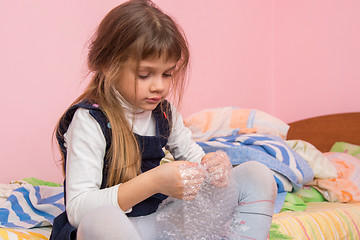 Image showing Sad girl sitting on the bed and eats bubbles on the packaging film