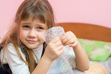 Image showing Five-year girl listens to burst like bubbles on the packaging bag