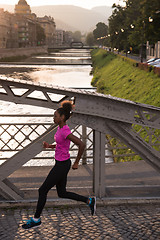 Image showing african american woman running across the bridge