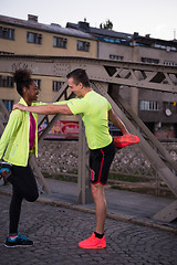 Image showing jogging couple warming up and stretching in the city