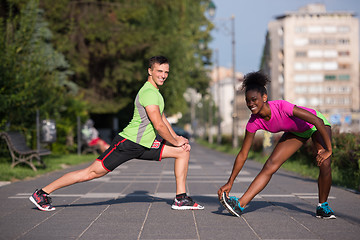 Image showing jogging couple warming up and stretching in the city