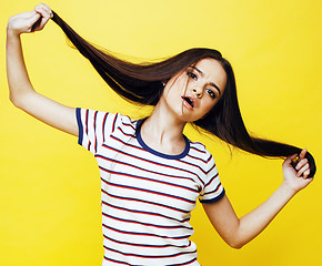 Image showing young pretty teenage woman emotional posing on yellow background, fashion lifestyle people concept