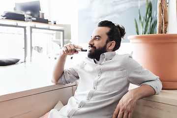 Image showing smiling man with beard and hair bun at office