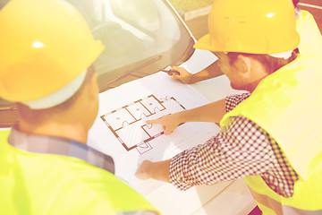 Image showing close up of builders with blueprint on car hood