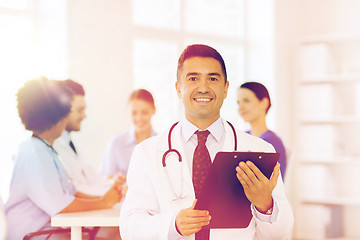 Image showing happy doctor with clipboard over medical team