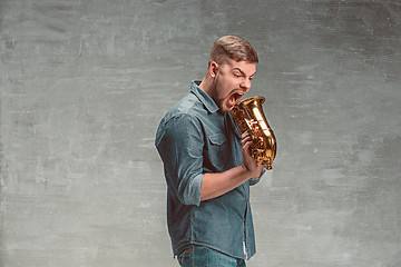 Image showing Happy saxophonist with sax over gray background