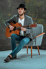 Image showing Cool guy with hat playing guitar on gray background