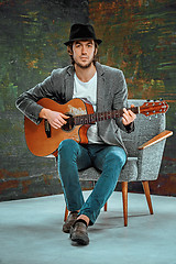 Image showing Cool guy with hat playing guitar on gray background