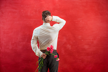 Image showing Man holding bouquet of carnations behind back