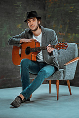 Image showing Cool guy with hat playing guitar on gray background