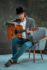 Image showing Cool guy with hat playing guitar on gray background