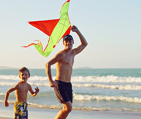 Image showing father with son, sunset at the seacoast playing kite, happy family 