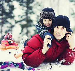 Image showing portrait of happy father with his son outside with snowman close