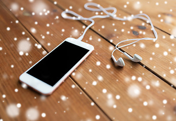 Image showing close up of blank smartphone and earphones on wood