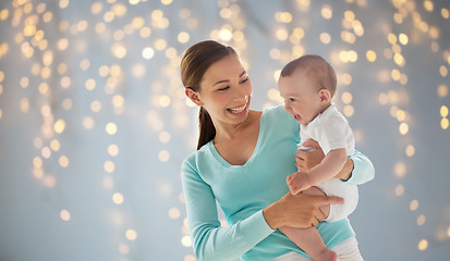 Image showing happy young mother with little baby over lights