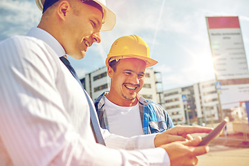 Image showing happy builders in hardhats with tablet pc outdoors