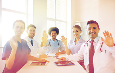 Image showing happy doctors meeting and waving hands at hospital