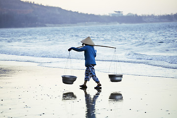 Image showing vietnam woman in vietnamese hat walking on seacost at sunset