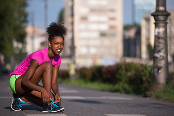 Image showing African american woman runner tightening shoe lace