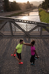 Image showing jogging couple warming up and stretching in the city