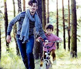 Image showing father learning his son to ride on bicycle outside in green park, lifestyle people concept