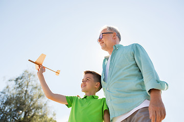 Image showing senior man and boy with toy airplane over sky