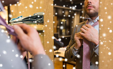 Image showing close up of man tying tie at clothing store mirror
