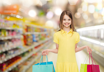 Image showing smiling girl with shopping bags over supermarket