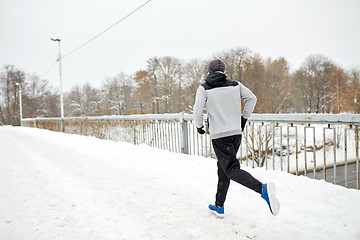 Image showing man running along snow covered winter bridge road