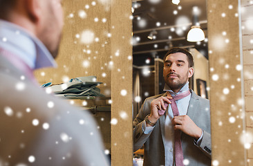 Image showing man tying tie on at mirror in clothing store