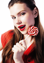 Image showing young pretty brunette girl with red candy posing on white backgr