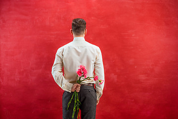 Image showing Man holding bouquet of carnations behind back