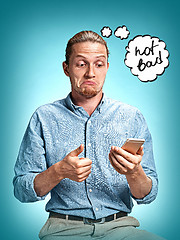 Image showing The young surprised caucasian businessman on blue background talking by cell phone