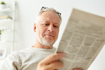 Image showing close up of senior man reading newspaper at home