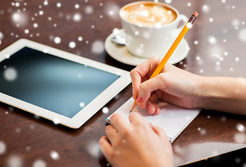 Image showing woman with tablet pc writing to notebook