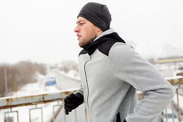 Image showing man running along winter bridge